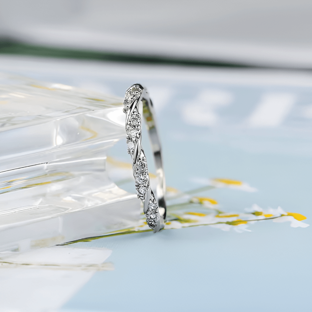 Alliance Torsade de Moissanite pour femme en argent 925 posée sur un échiquier transparant. Bague diamant et or blanc 18K pour célébrer un mariage.