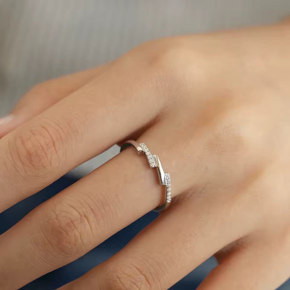 Alliance asymétrique en acier inoxydable et or blanc sertie d'oxydes de zirconium portée au doigt d'une femme vue de face.