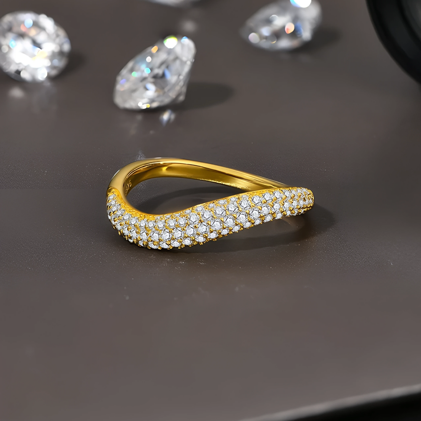 Alliance Courbée Sertie de Diamants en or jaune à plat sur une table de travail de joaillier.