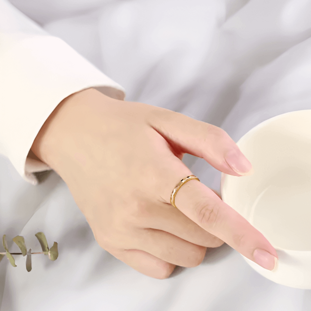 Alliance facettée de 4mm en tungstène et or jaune portée au doigt d'une femme.