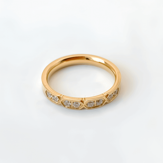 Alliance gravée alvéolée en acier inoxydable et or jaune sertie de cristaux sur fond blanc.