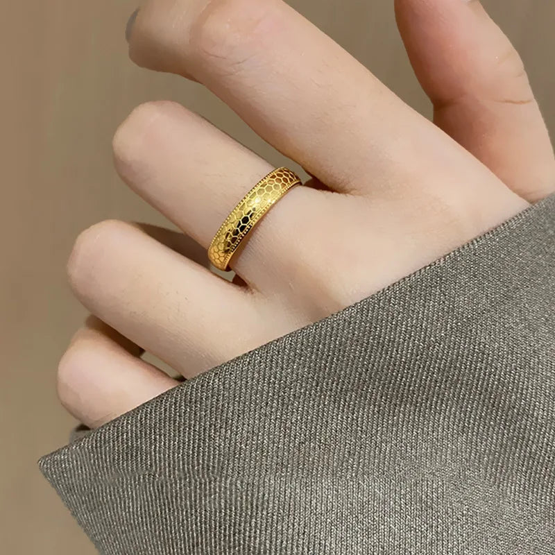 Alliance gravée en acier inoxydable et or jaune portée au doigt d'une femme.