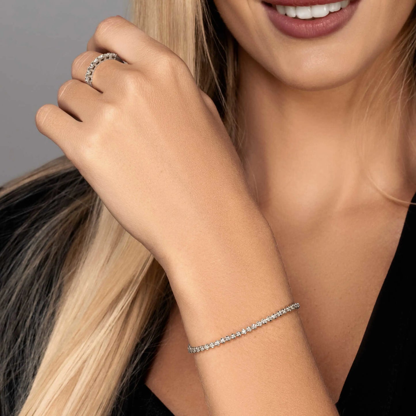 Main de femme portant au doigt une alliance sertie de diamants ronds variante or blanc.