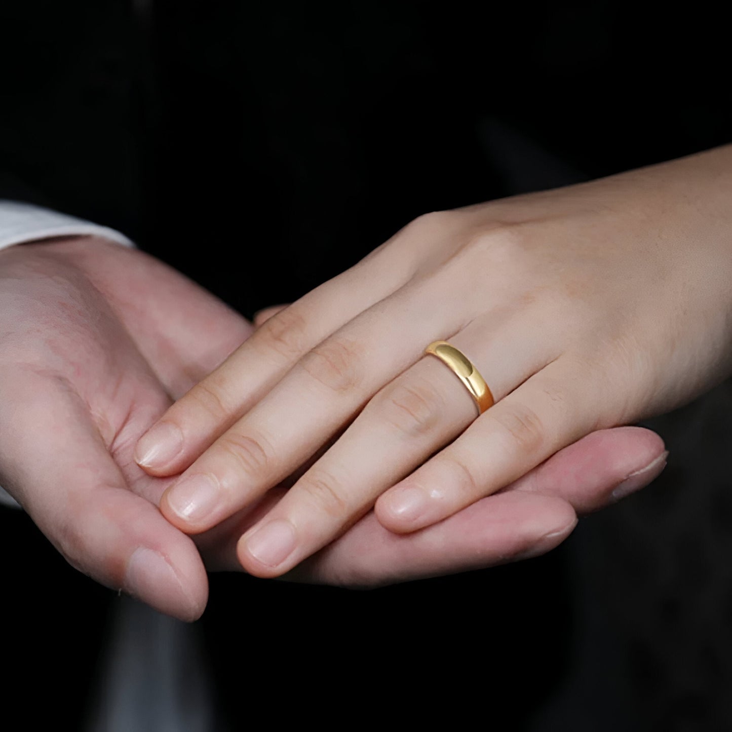 Main de femme portant au doigt une alliance Homme Femme en or jaune.