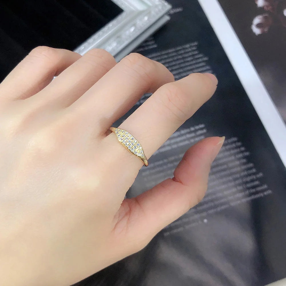 Alliance pavé en or jaune et oxydes de zirconium portée au doigt d'une femme vue de loin.