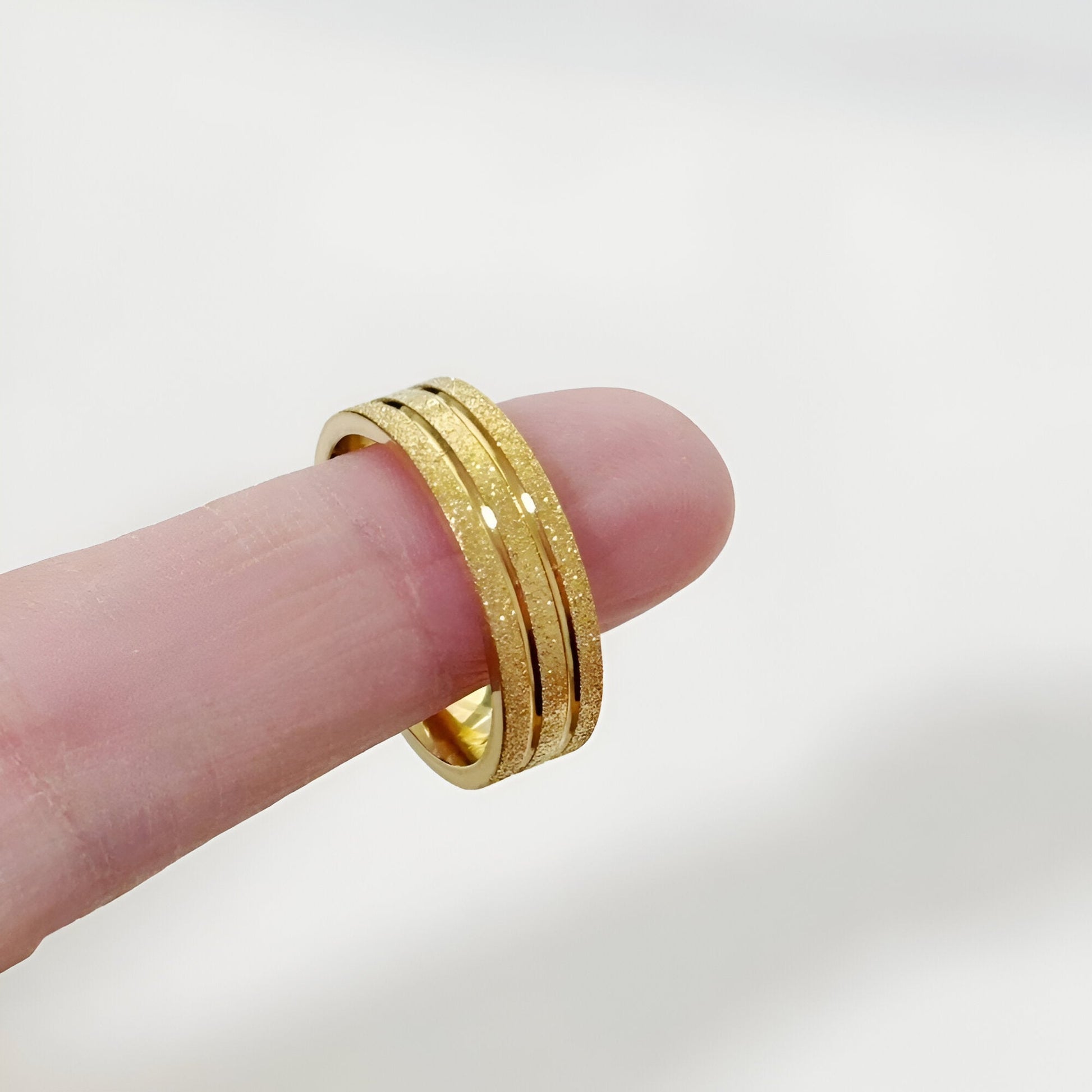 Alliance ruban en acier inoxydable et or jaune montrée au bout d'un doigt.