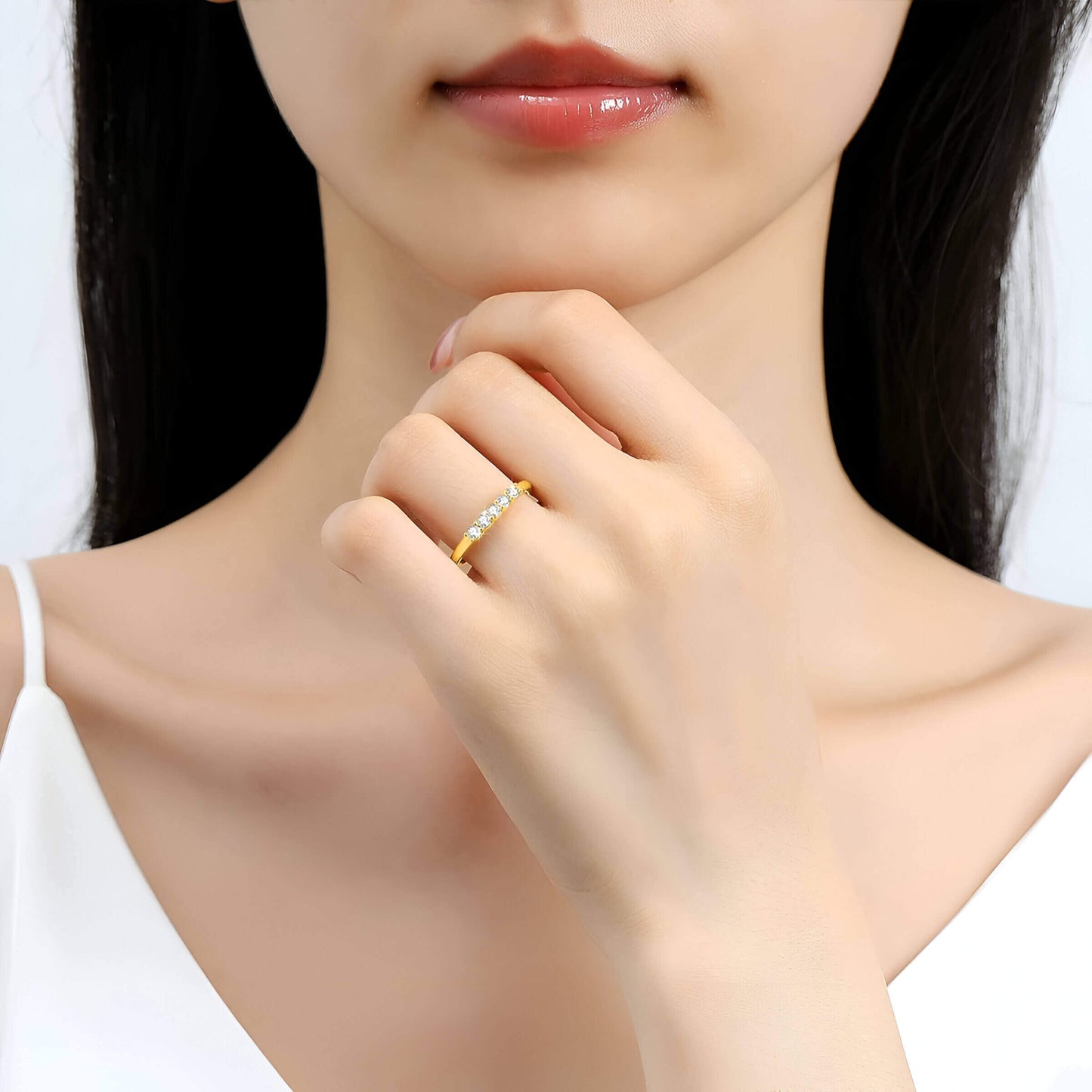 Alliance semi-éternité en or jaune et diamants synthétiques portée au doigt d'une femme.