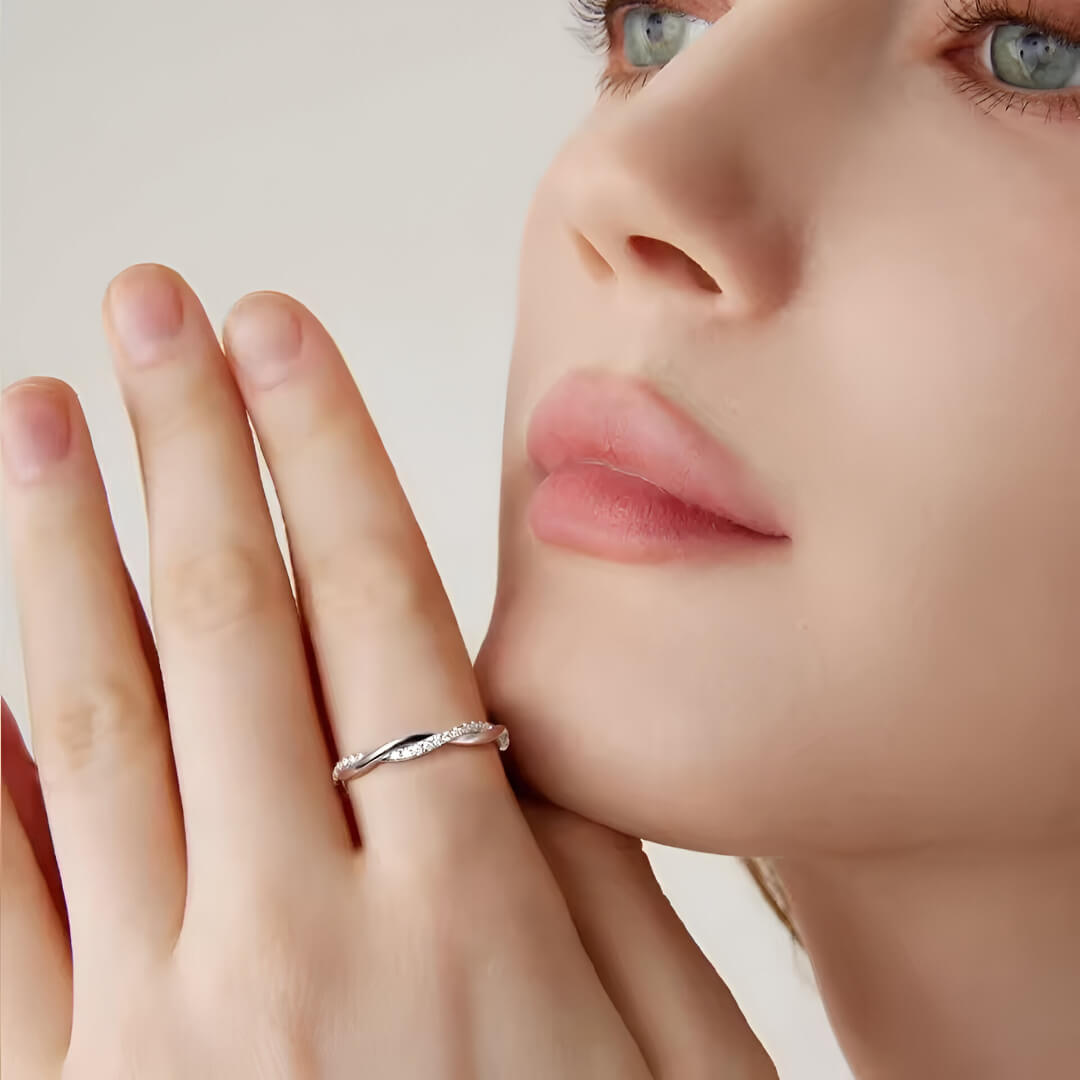 Alliance torsadée en or blanc et diamants synthétiques portée à l'index d'une femme.