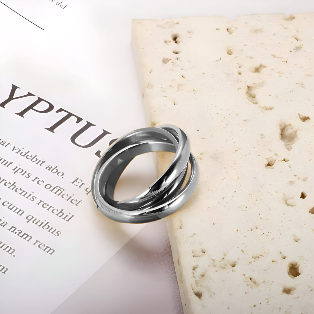 Alliance triple demi-jonc en acier plaqué or blanc posée sur une pierre blanche.