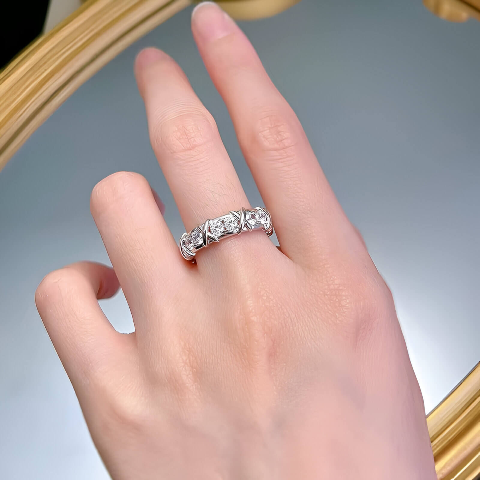 Alliance x en or blanc et diamant naturel portée au doigt d'une femme.