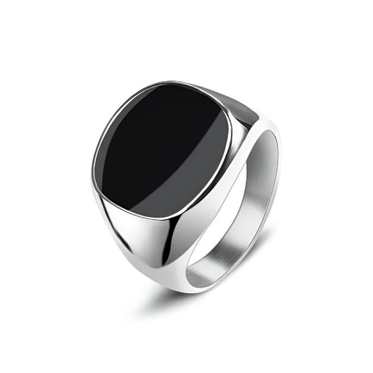 Bague chevalière en acier et or blanc sertie d'onyx sur fond blanc.