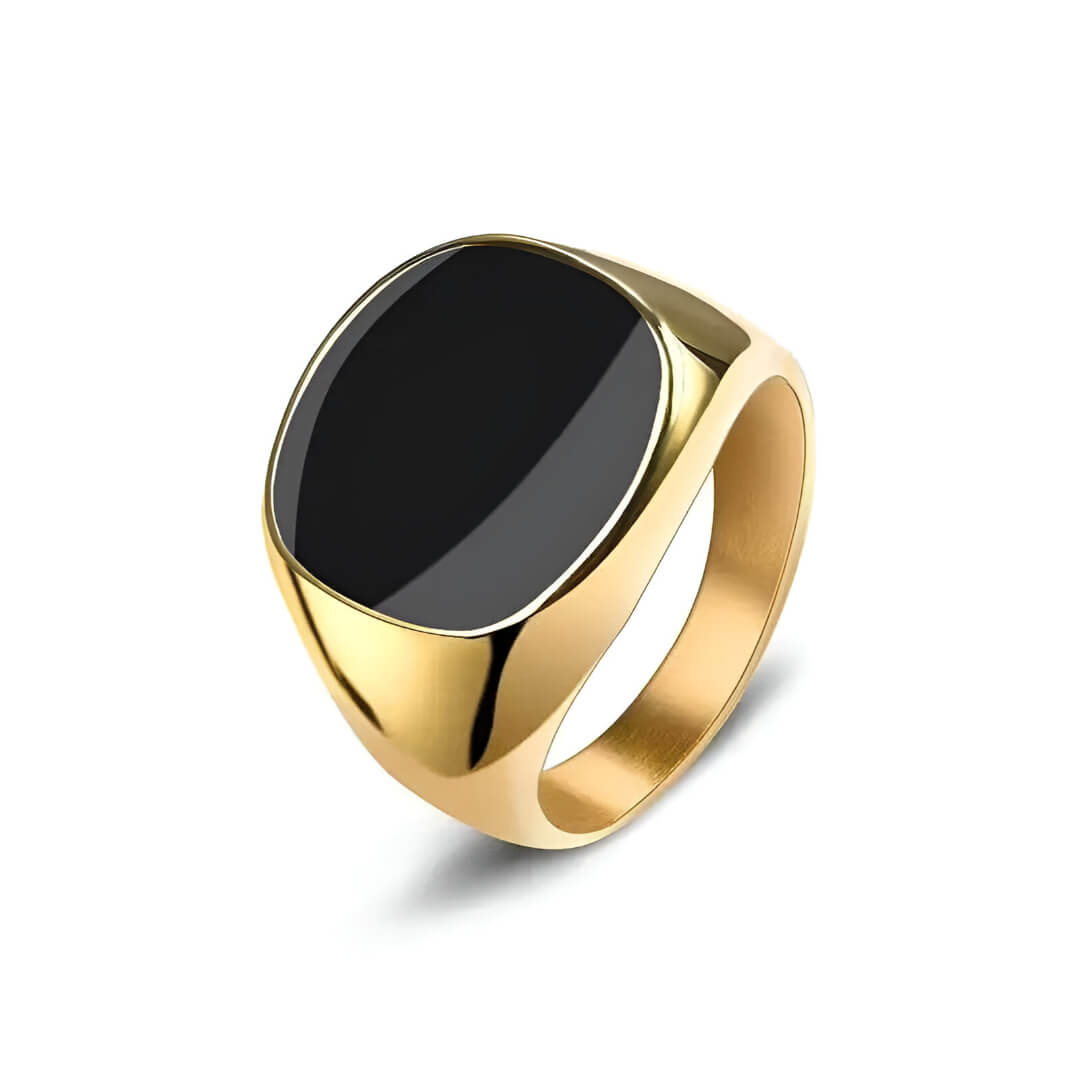 Bague chevalière en acier et or jaune sertie d'onyx sur fond blanc.