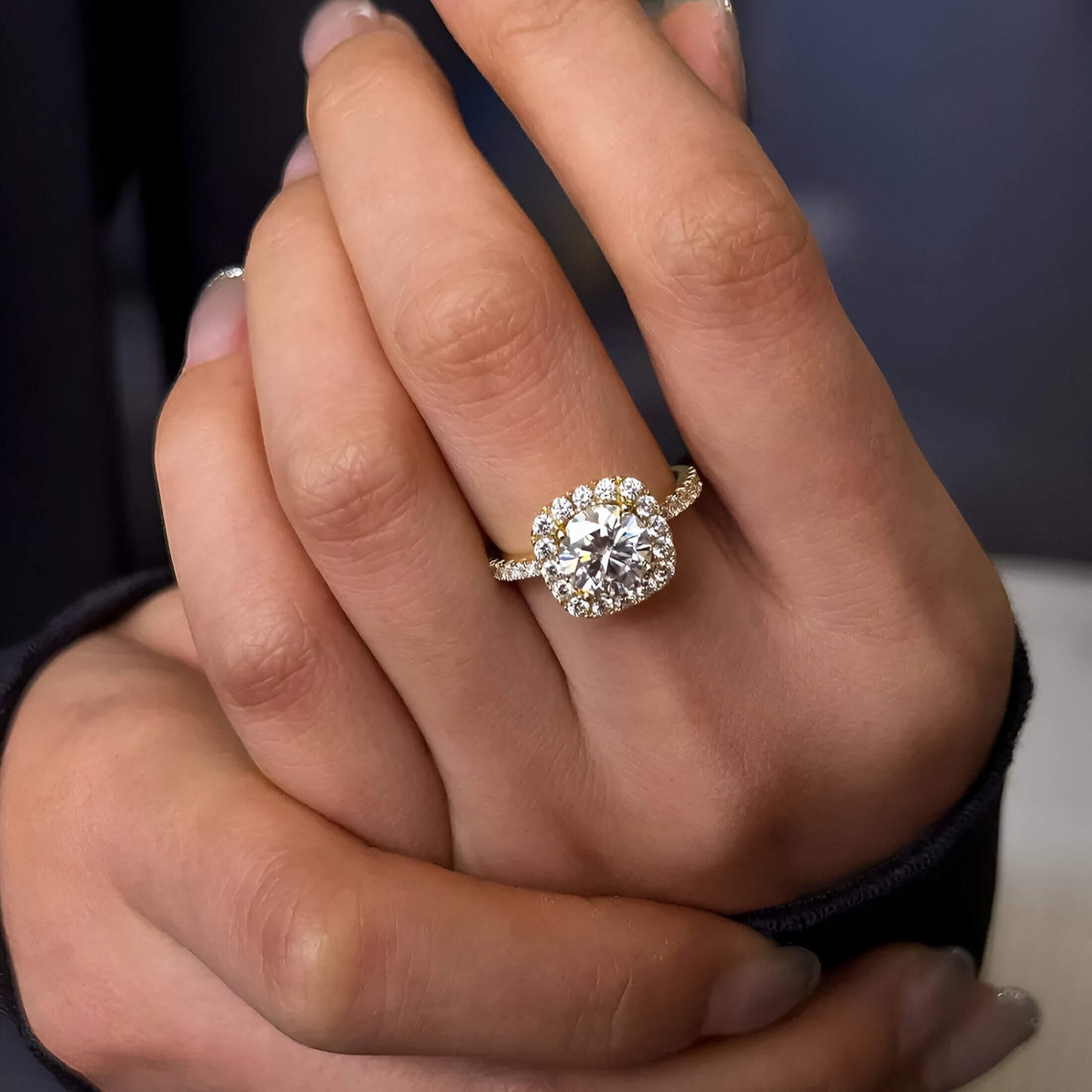 Bague de fiançailles en argent plaqué or jaune avec diamant centrale en moissanite étincelante et zircon naturels de forme ronde portée au doigt d'une femme.