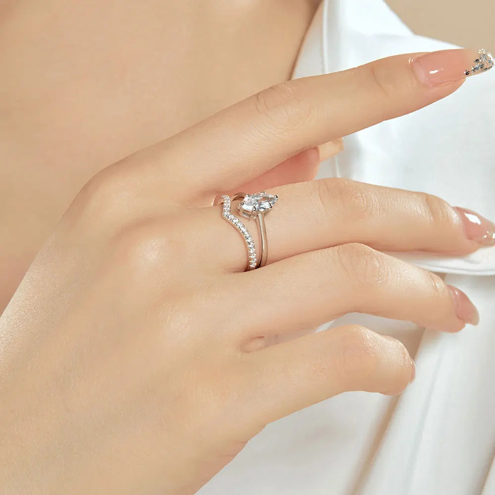 Bague duo de fiançailles en or blanc et diamants synthétiques portée au doigt d'une femme vue de côté.