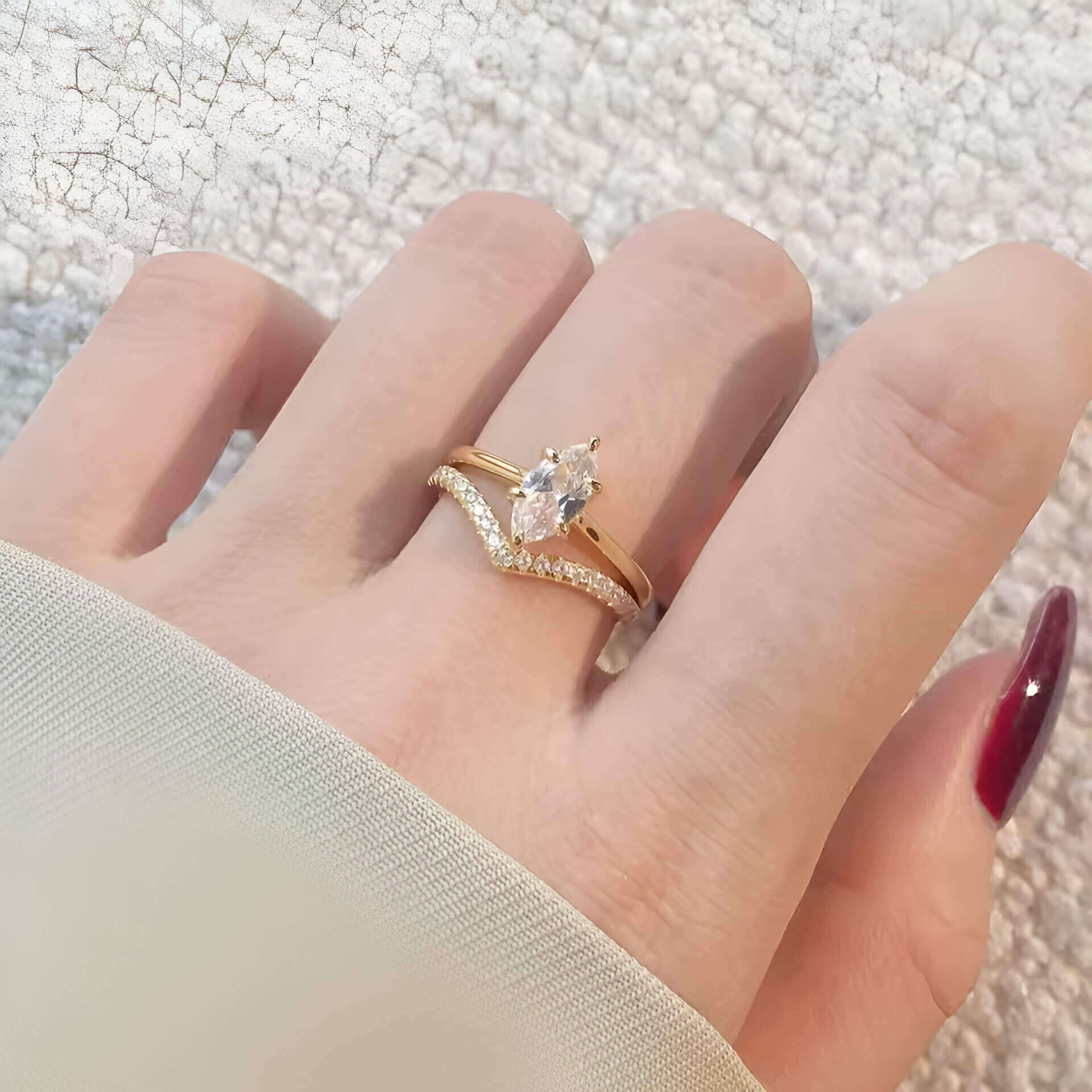 Bague duo de fiançailles en or jaune et diamants synthétiques portée au doigt d'une femme vue du dessus.