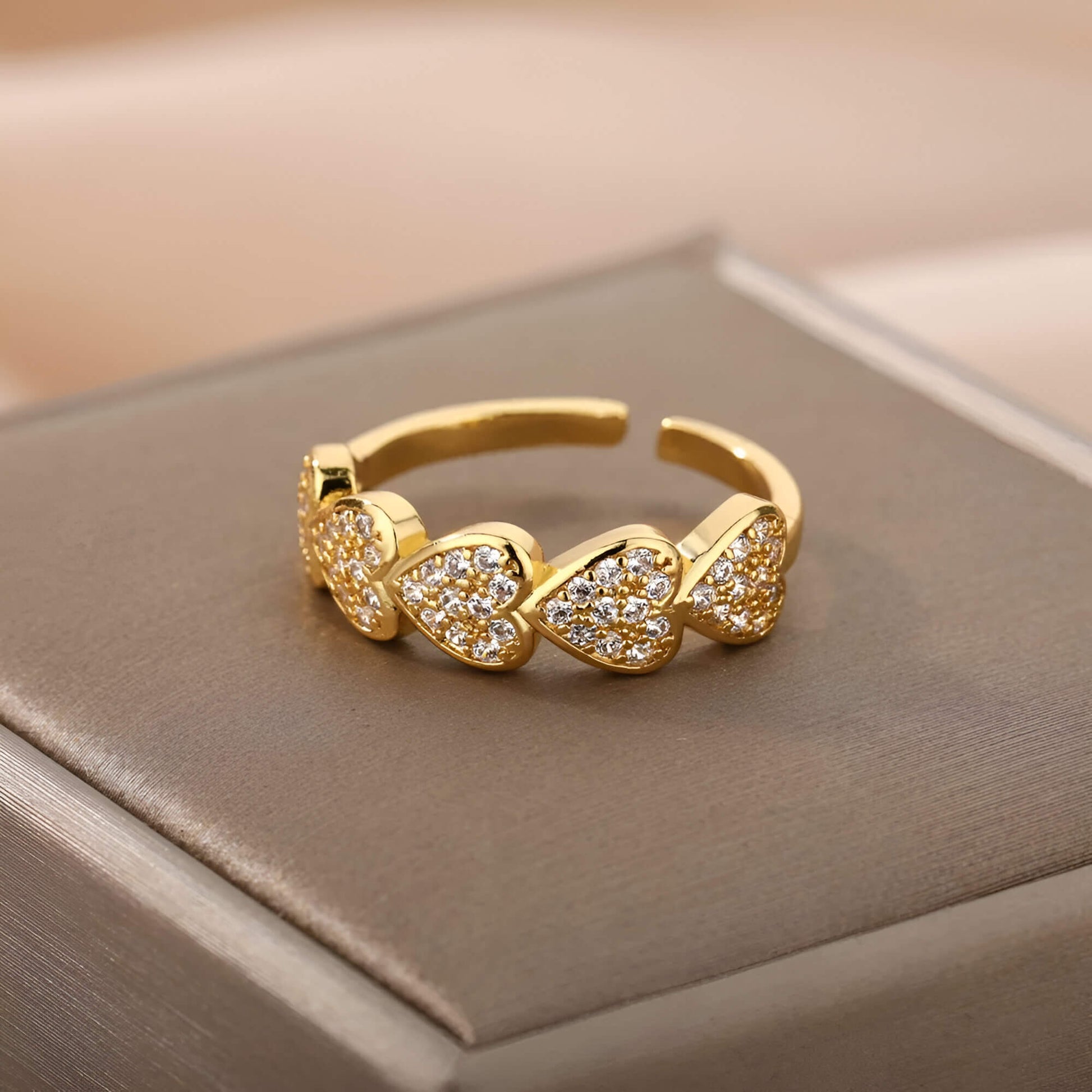 Bague fantaisie ouverte cœurs en acier et or jaune sertie de diamants naturels vue de face sur un écrin.