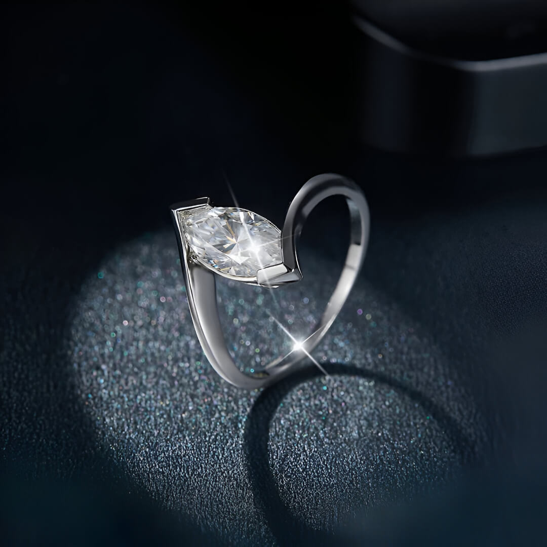 Bague moissanite marquise solitaire en argent debout vue de côté sur du granite noir.