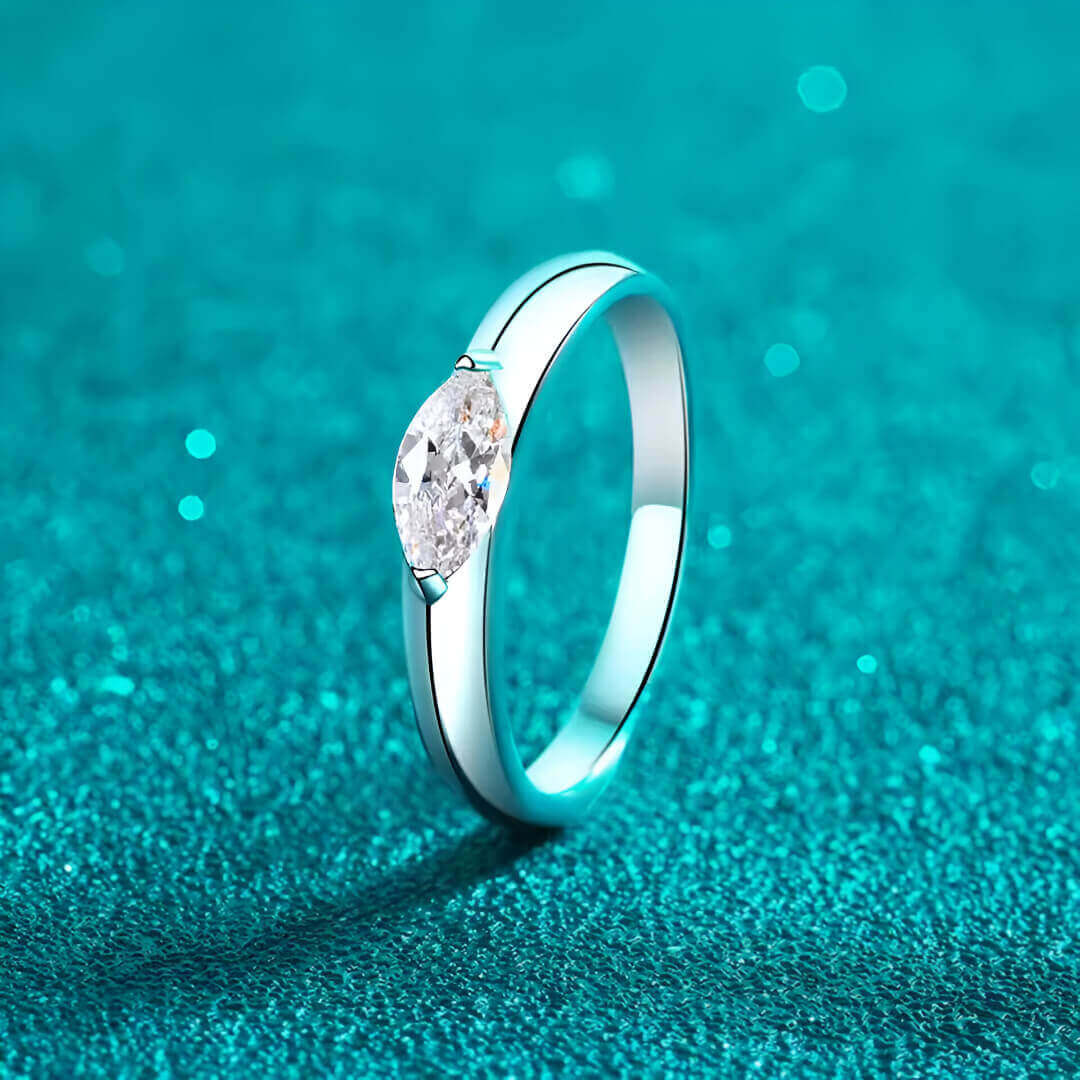 Bague solitaire dune de diamant debout vue de côté sur fond bleu cyan.