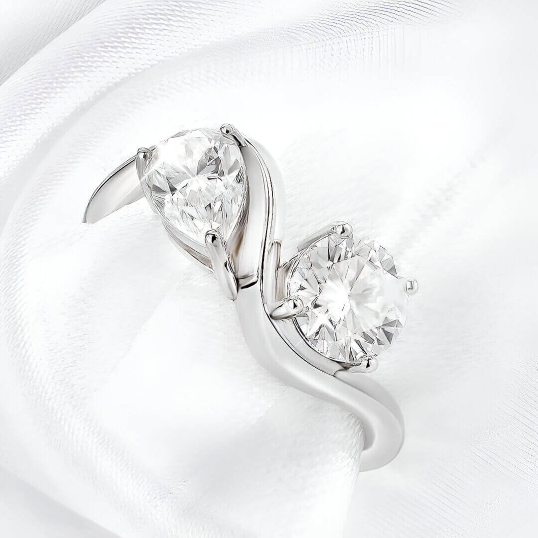 Bague ondulée paire de diamants portée par une nappe blanche vue du dessus.