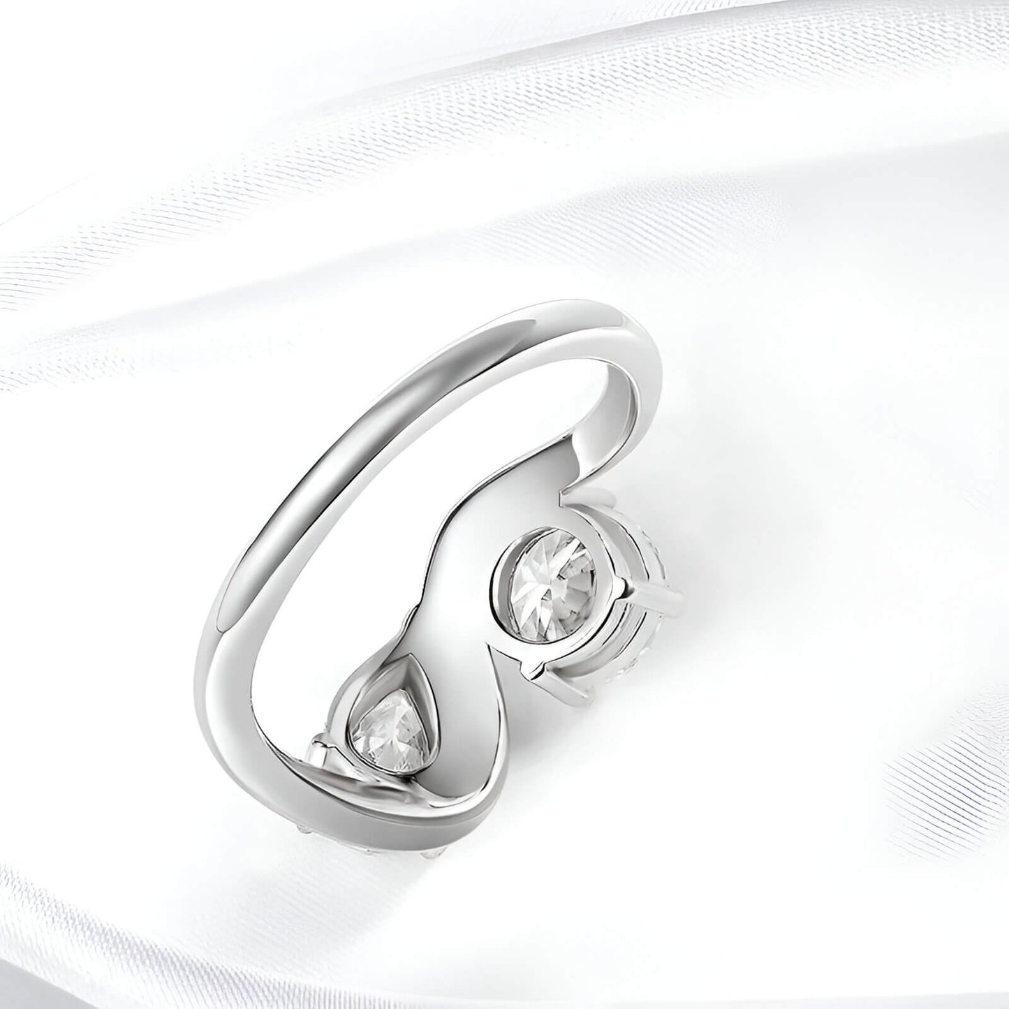 Bague ondulée paire de diamants vue de dos sur une nappe blanche.