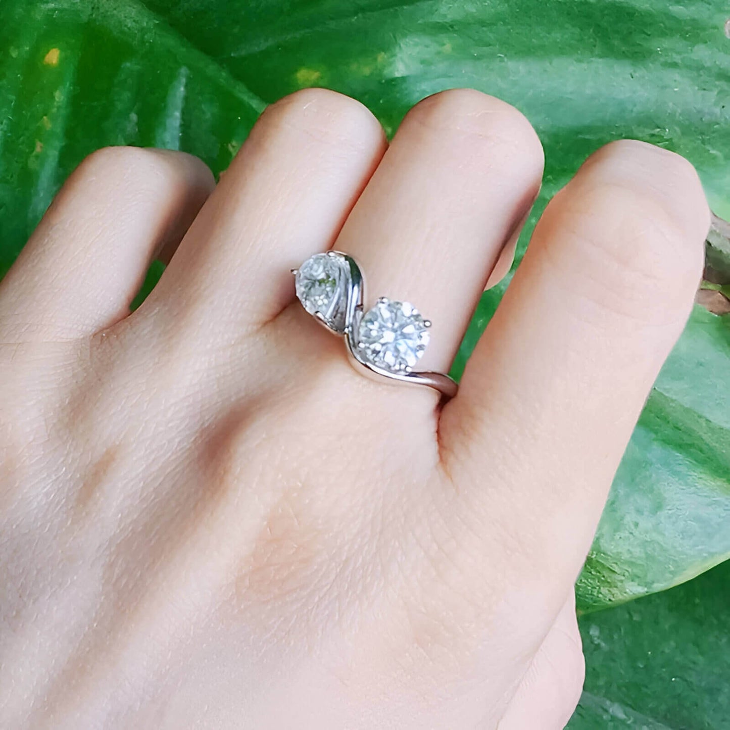 Bague ondulée paire de diamants portée au doigt d'une femme.