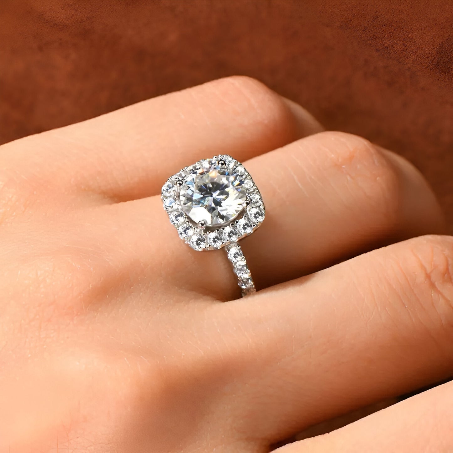 Main de femme portant au doigt une bague solitaire halo pavé de diamants en argent.