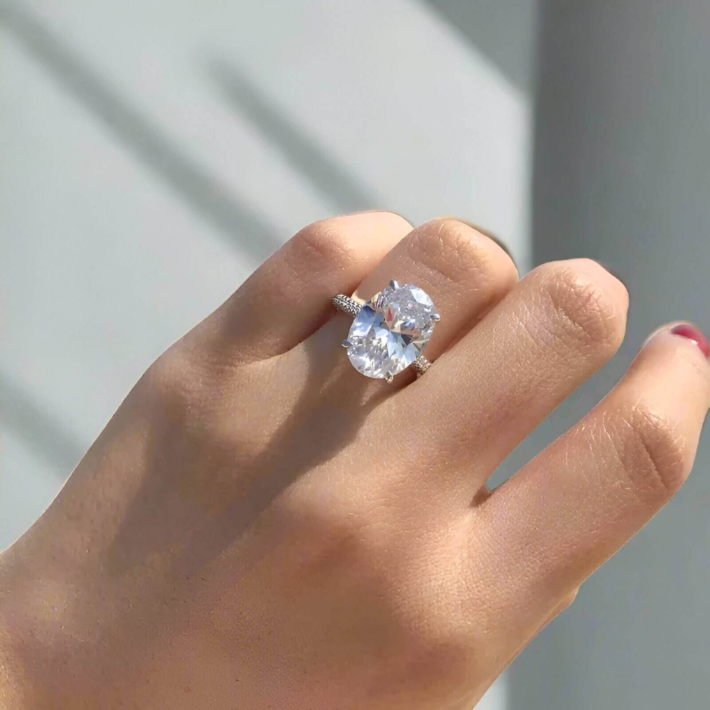 Femme portant au doigt une bague solitaire zircon ovale.