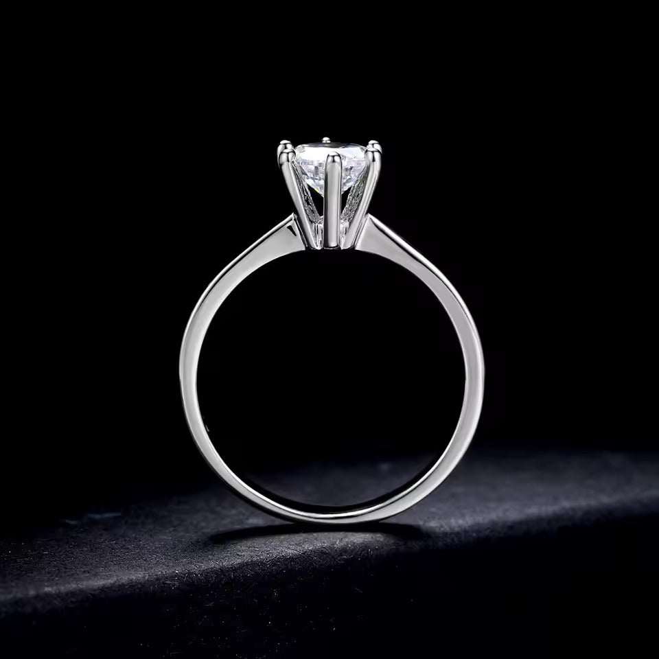 Bague solitaire six griffes en argent vue latérale sur fond noir.
