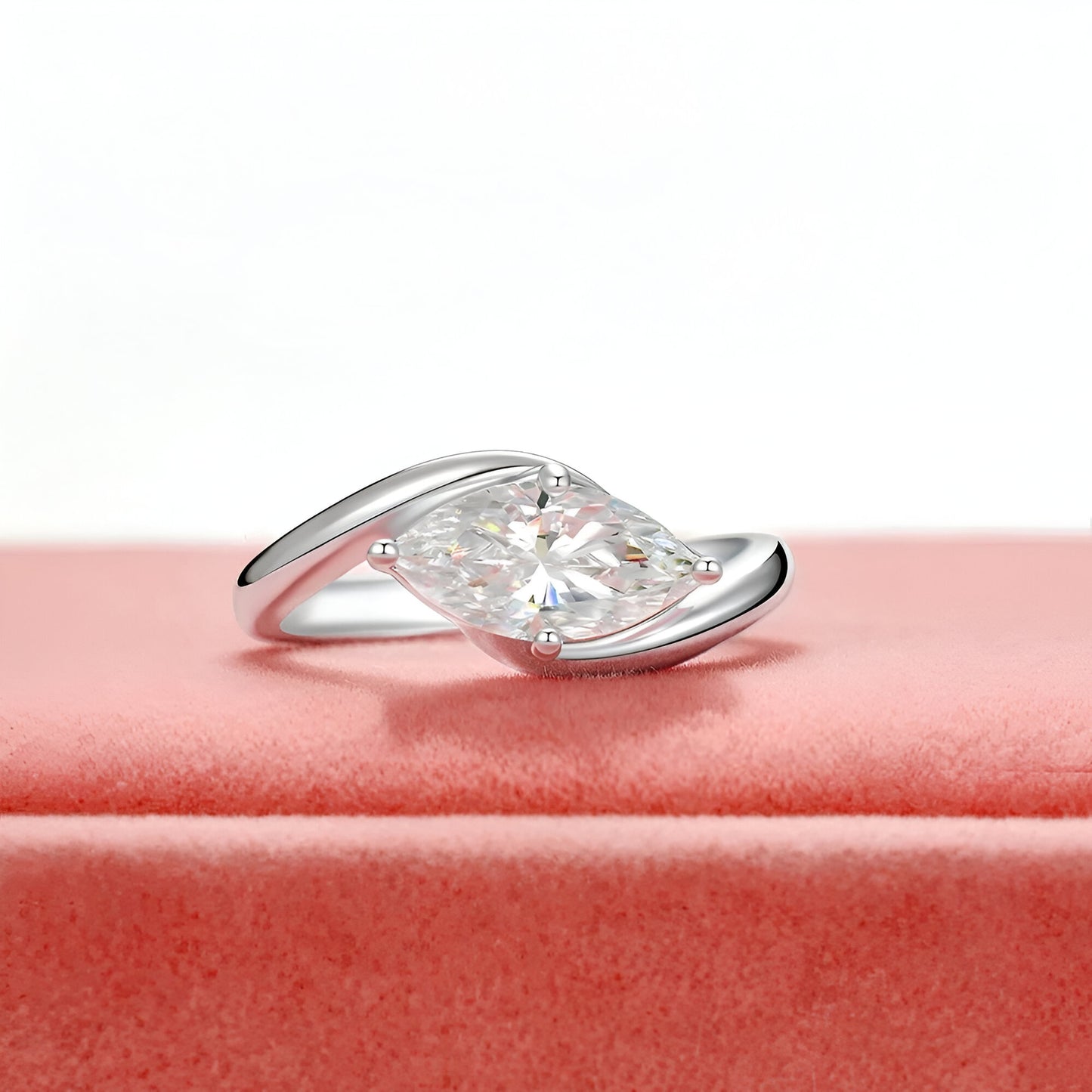 Bague diamant marquis solitaire à plat vue de face sur une surface rose bonbon.
