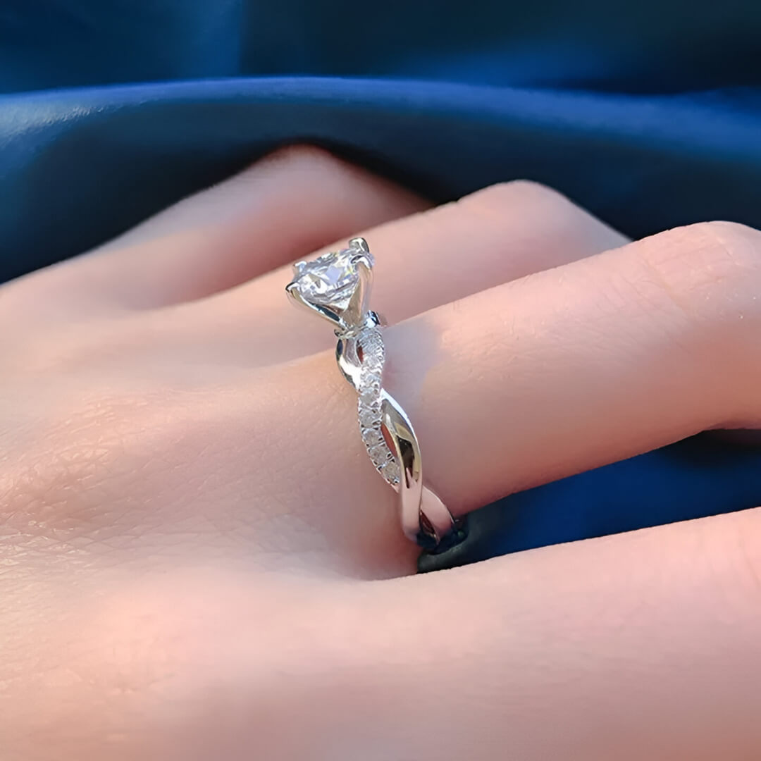 Bague solitaire tresse sertie de diamants vue de côté portée au doigt d'une femme.
