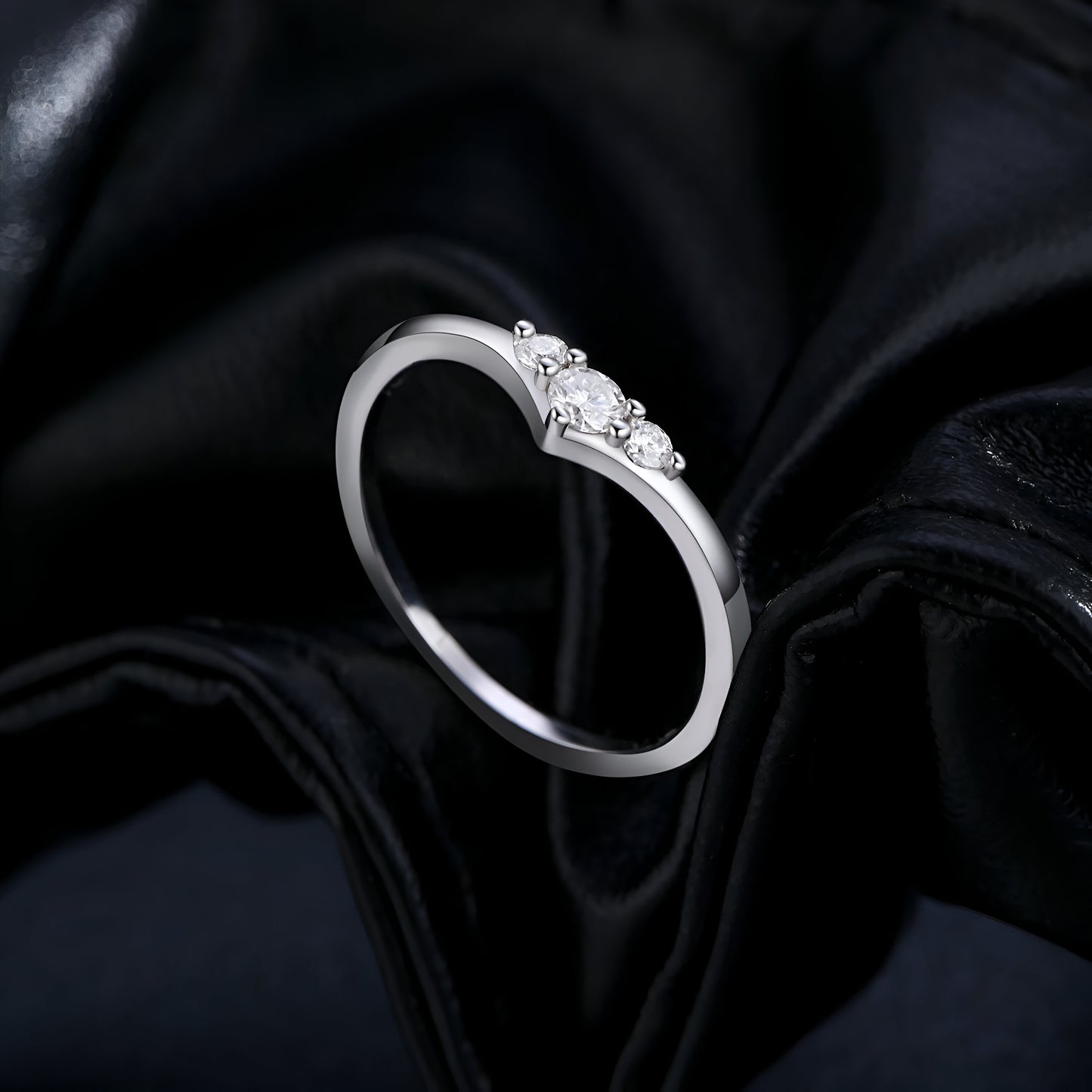 Bague trilogie triple moissanite vue de côté sur du cuire noir.