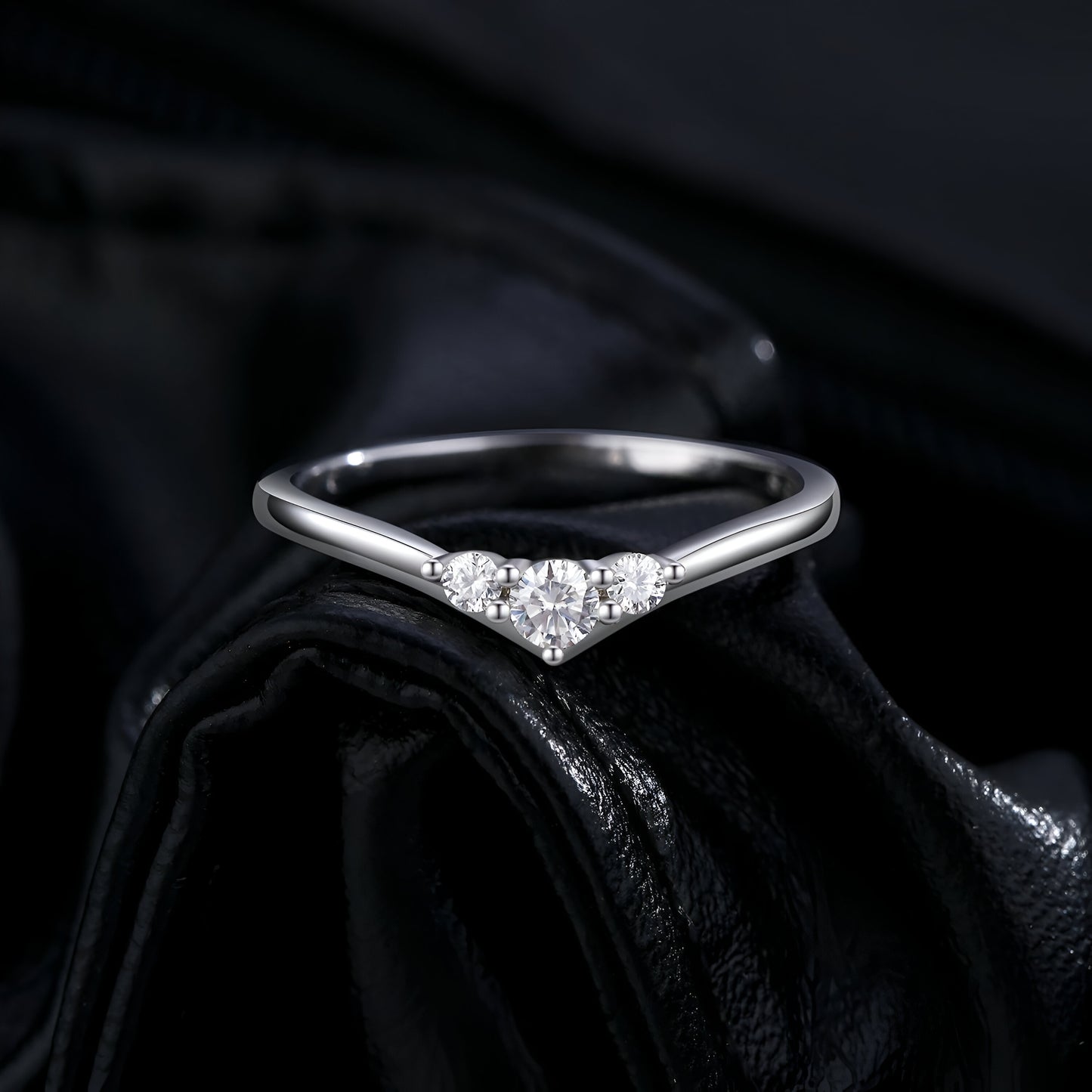 Bague trilogie triple moissanite vue de face sur du cuire noir.