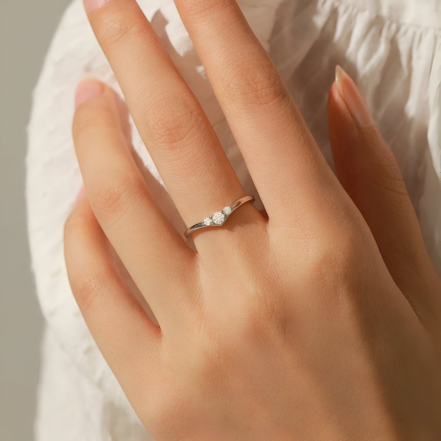 Main de femme portant au doigt une bague trilogie triple moissanite.