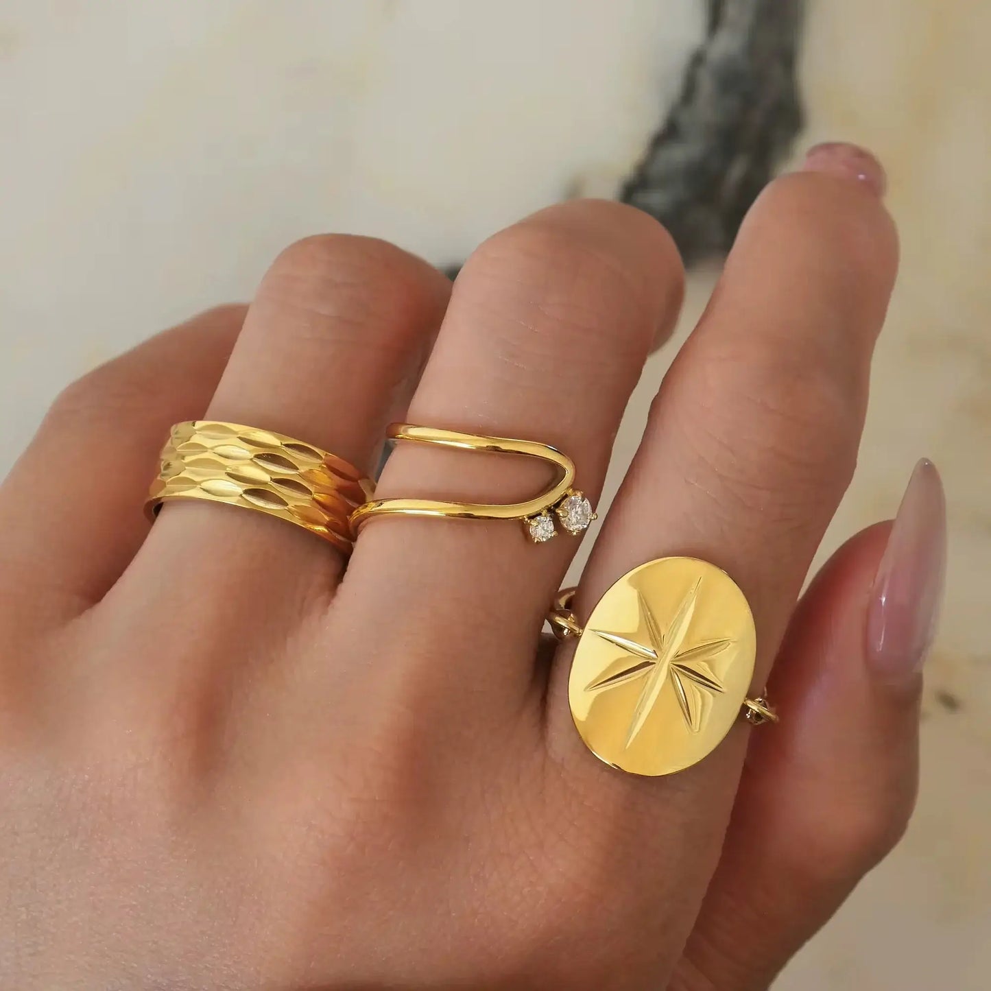 Bague fine courbée Spinela en acier plaqué or jaune 18K raffiné et oxydes de zirconium sertis quatre griffes portée au doigt d'une femme vue du dessus.