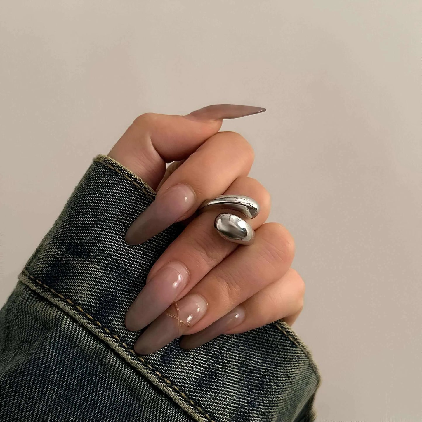 Bague goutte d'eau en acier inoxydable et or blanc portée au doigt d'une femme.