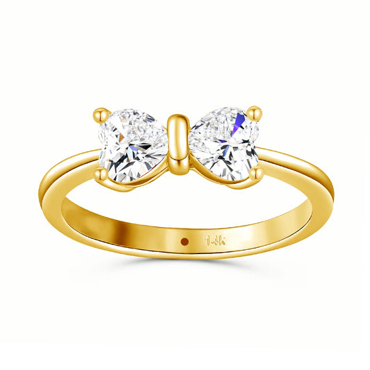 Bague nœud papillon en or jaune et diamants synthétiques sur fond blanc.