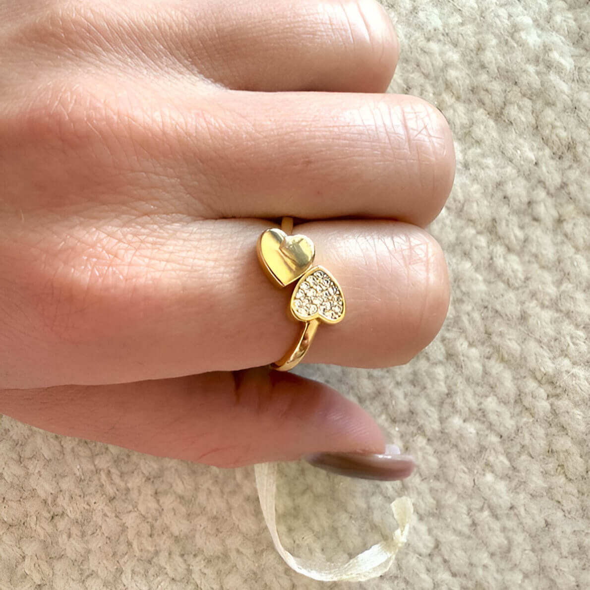 Bague fantaisie ouverte cœur en acier inoxydable et or jaune sertie de diamants naturels portée au doigt d'une femme.