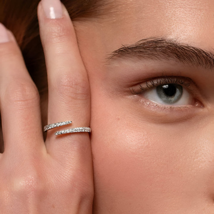 Bague ouverte en argent 925 éclat croisé portée par une femme, détails de zircons et finition en or blanc 14K, élégance subtile proche du visage - La Petite Rebelle