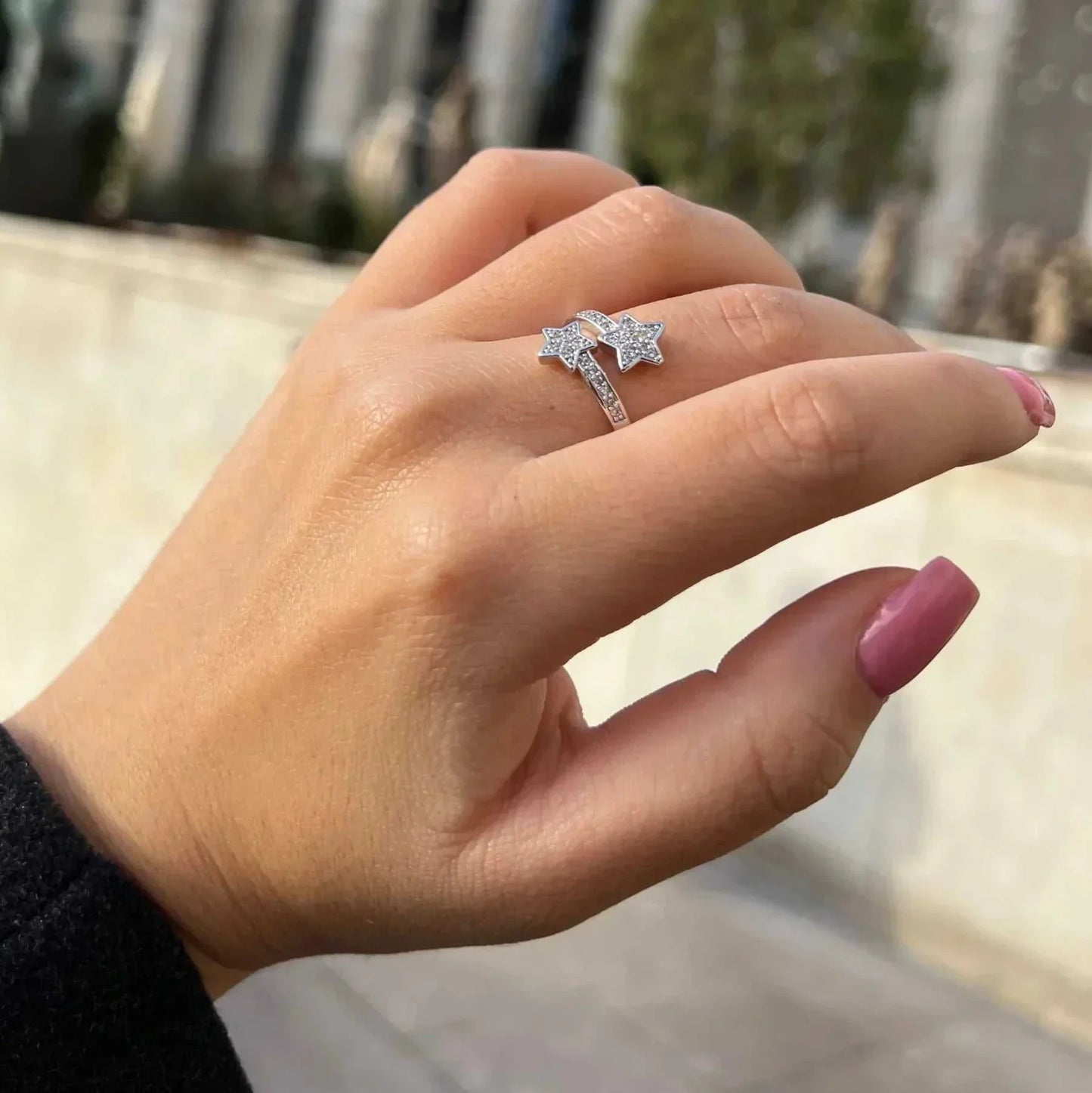 Main féminine élégante portant la BAGUE OUVERTE EN ARGENT ÉTOILES FILANTES, en acier inoxydable plaqué or blanc 18K, avec zircons scintillants.