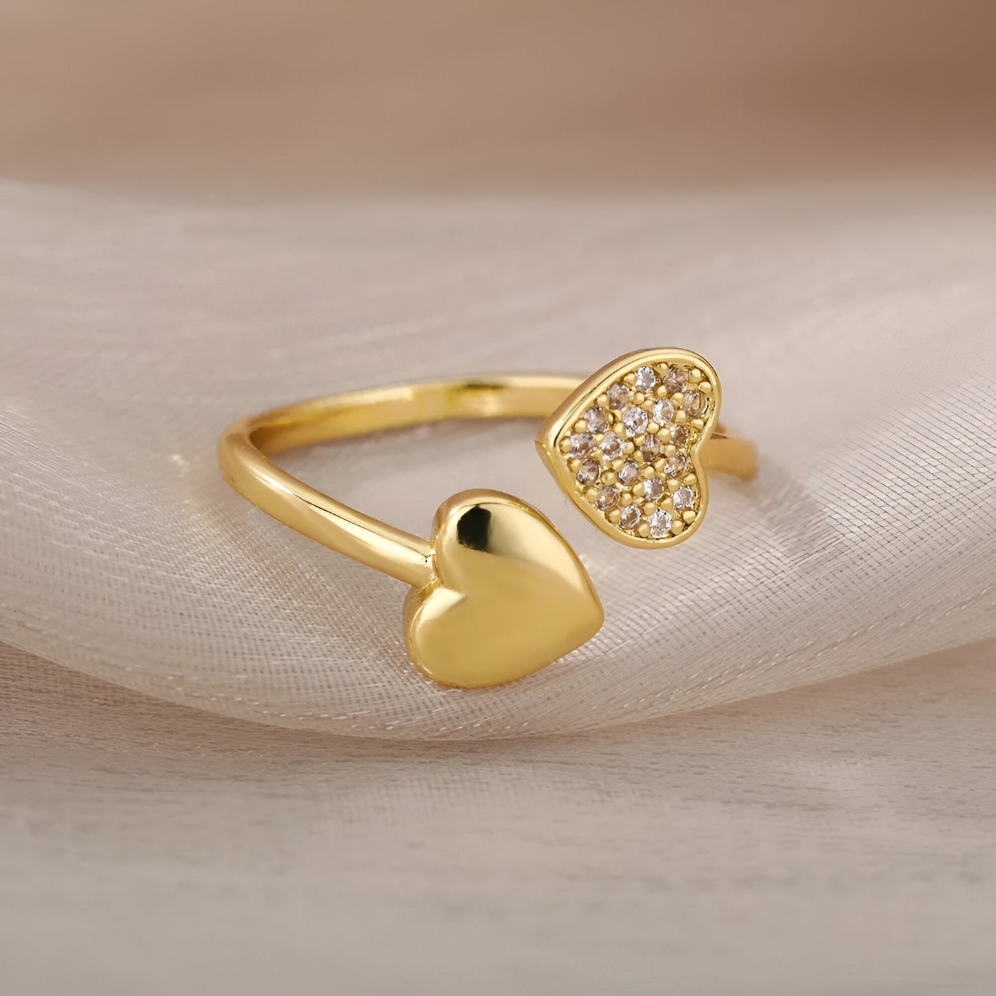 Bague ouverte en or avec duo de cœurs scintillants photographiée sur tissu – bague délicate en acier inoxydable plaqué or 18K, parfaite pour sublimer le quotidien
