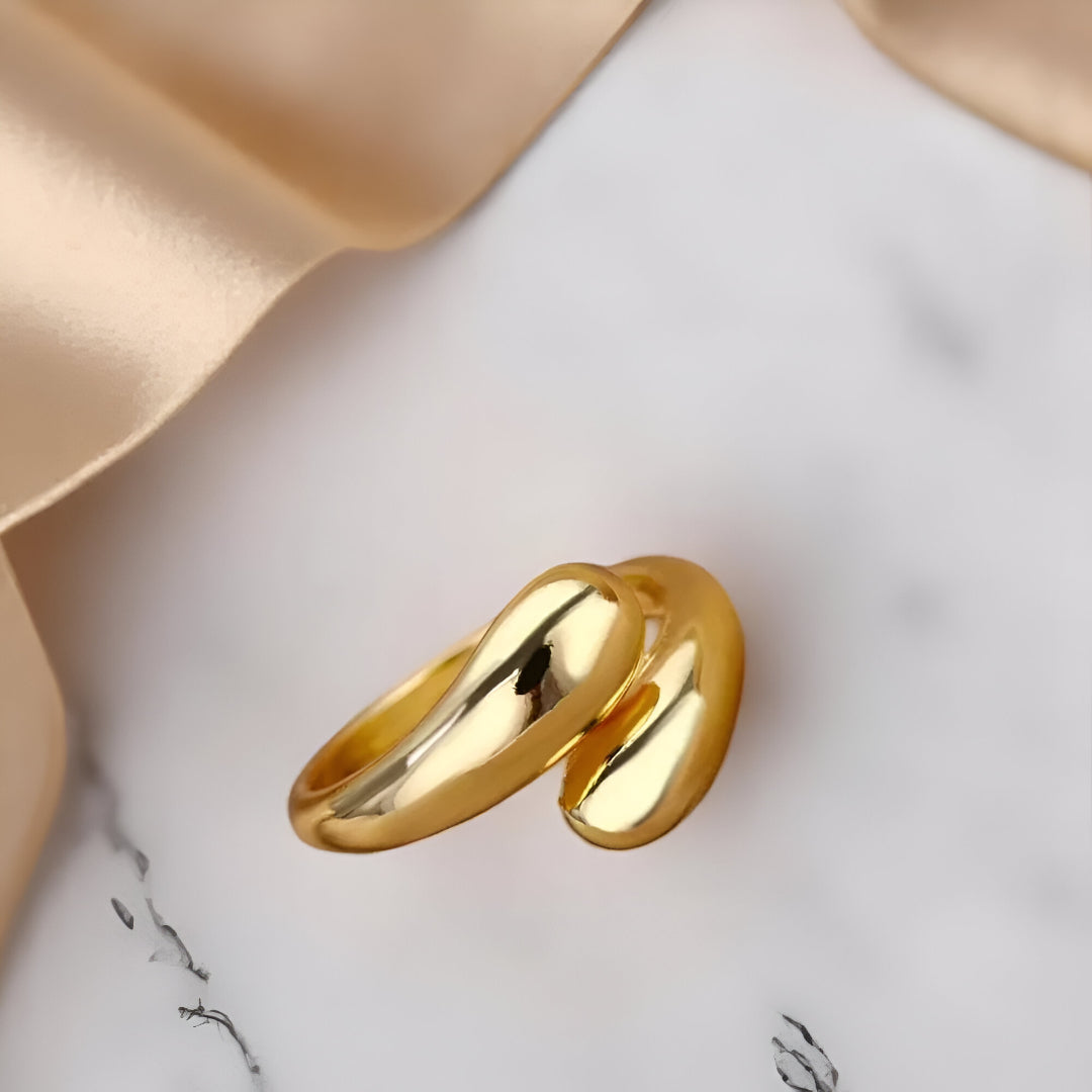 Bague ouverte en or Goutte d'eau vue inversée, plaqué or 14K, créant un contraste élégant avec le marbre blanc. Un choix de bijou haut de gamme pour un style unique.