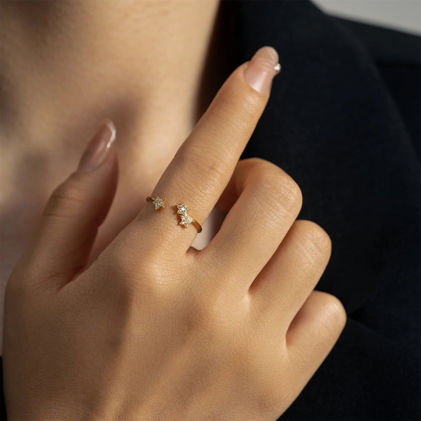 Bague ouverte étoile en or jaune et sertie de diamants naturels portée au doigt d'une femme.