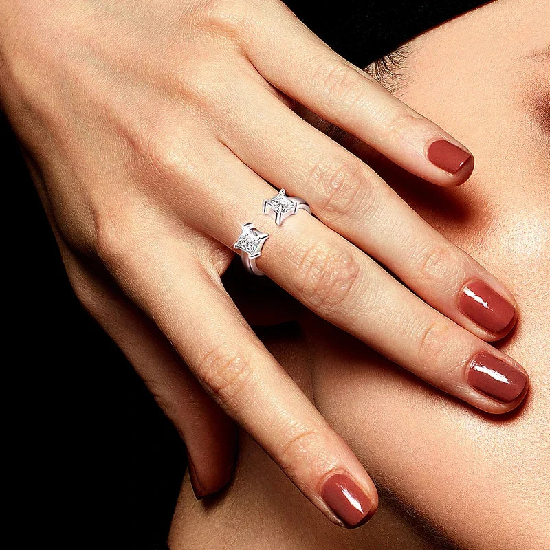Bague ouverte en or blanc et diamants synthétiques portée au doigt d'une femme.
