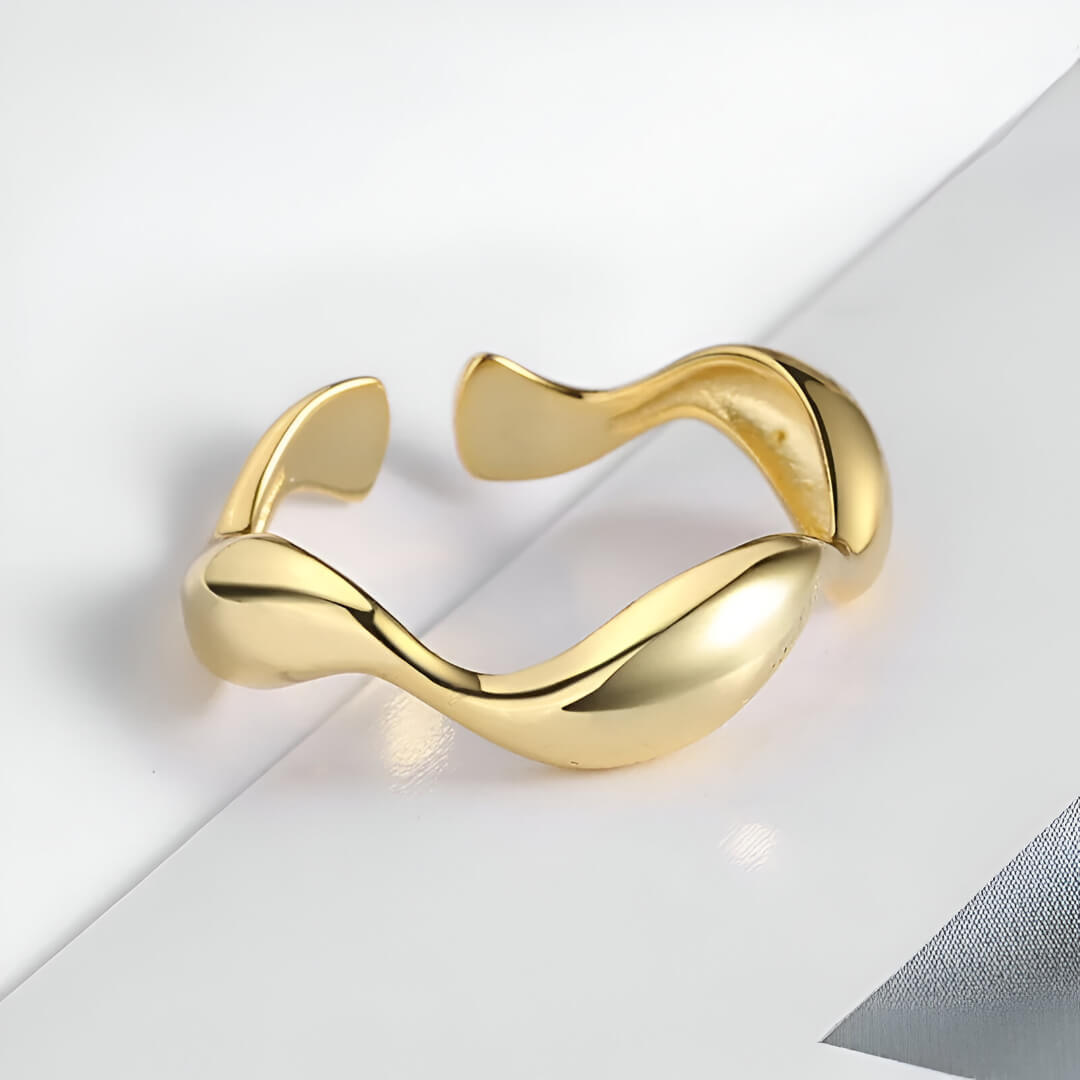 Bague ouverte ondulée en or jaune à plat.