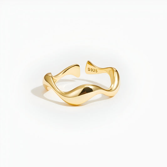 Bague ouverte ondulée en or jaune sur fond blanc.