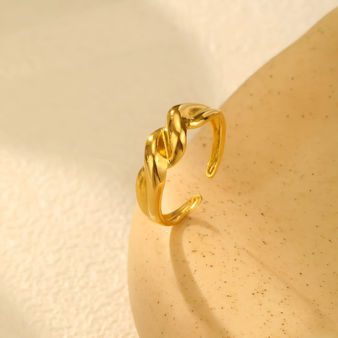 Bague ouverte torsadée en acier inoxydable et or jaune debout.