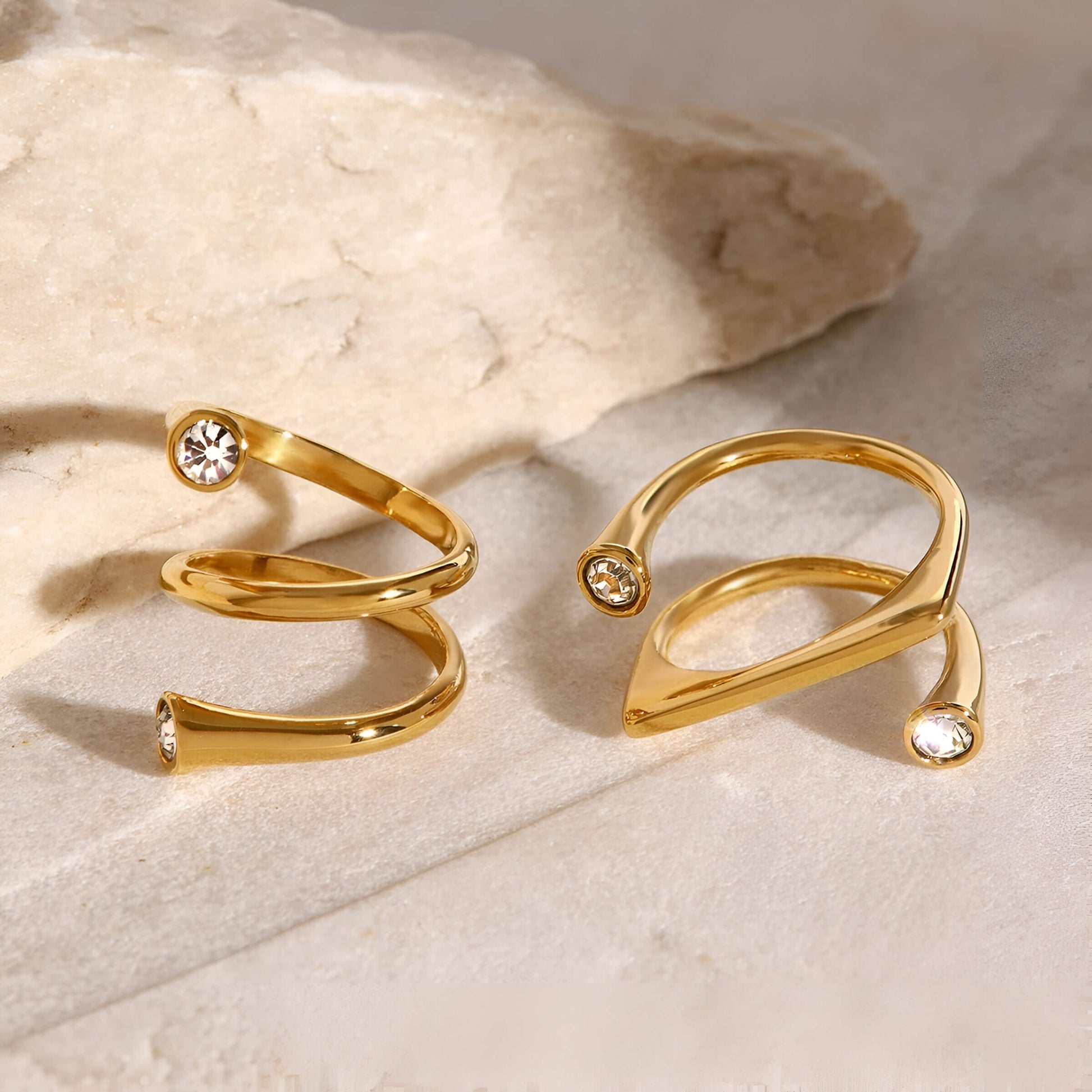 Bagues fantaisie ouverte tourbillon et semi-tourbillon en acier inoxydable et or jaune serties de cristaux vue côte  côte.