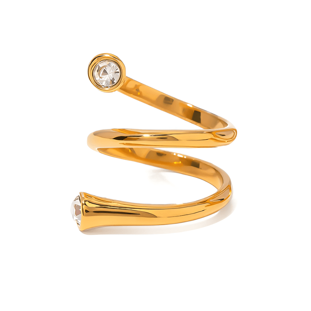 Bague fantaisie ouverte tourbillon en acier inoxydable et or jaune sertie de cristaux sur fond blanc.