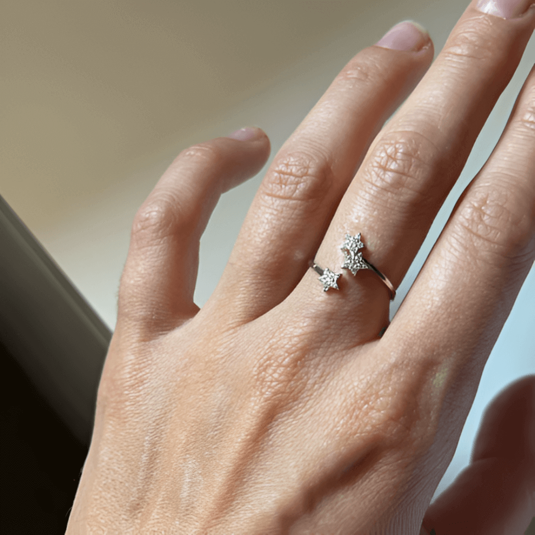Bague ouverte trio d'étoiles en argent 925 rhodié et zircons sertis grains portée au doigt d'une femme vue de face.