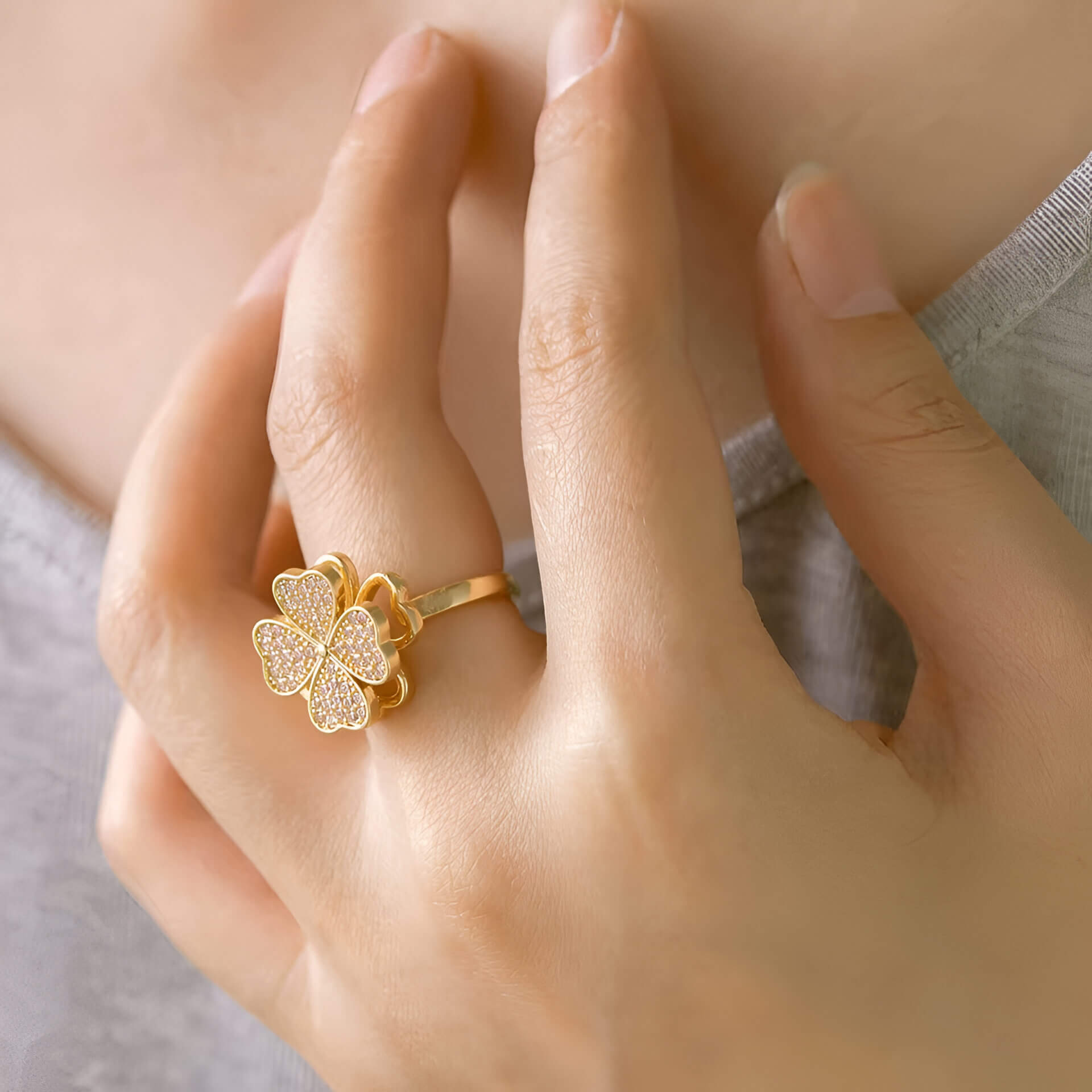 Bague rotative en acier doré et oxydes de zirconium portée au doigt d'une femme.